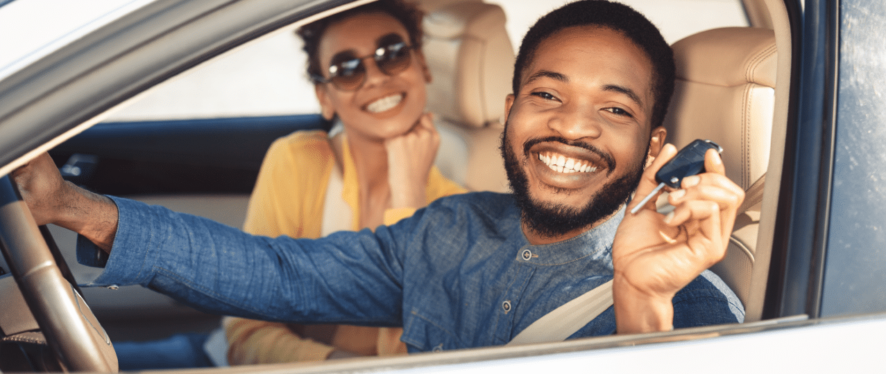 Happy couple in their new car holding car keys