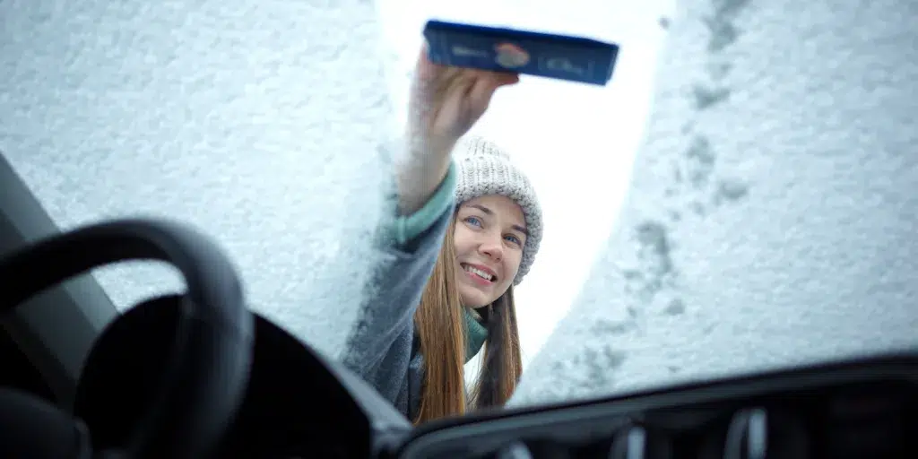 Girl cleaning her windshield from ice